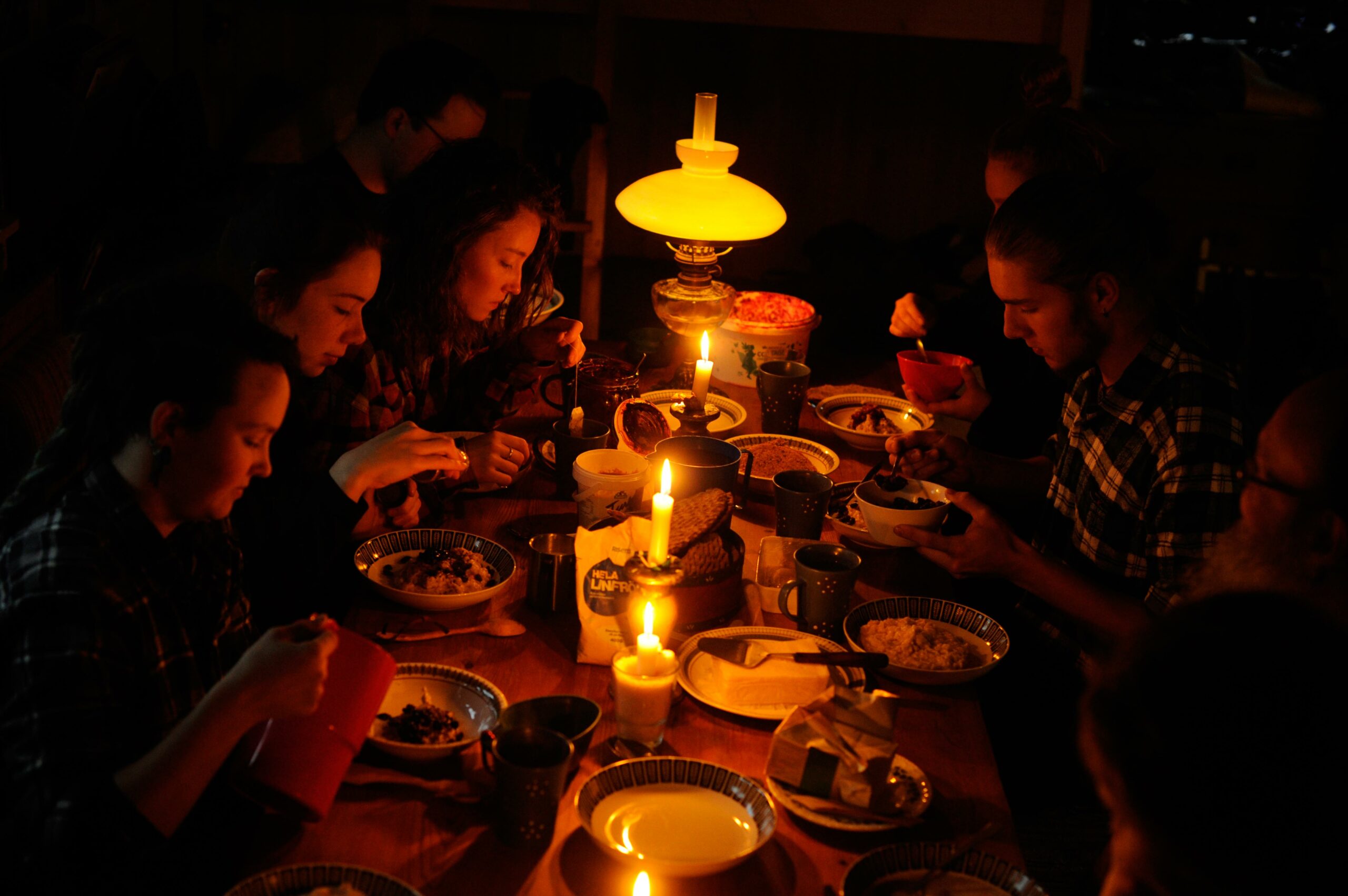 Sju människor äter middag i skenet av levande ljus.