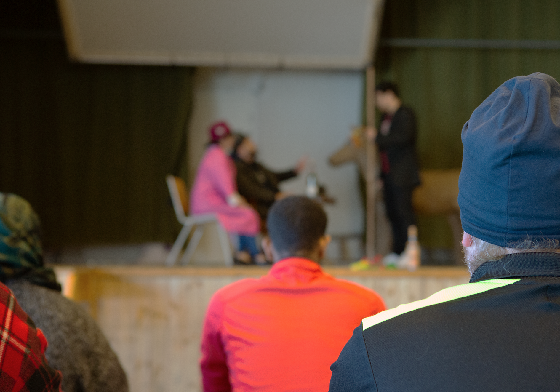 En grupp kursdeltagare i förgrunden betraktar ett verk som framförs på en scen
